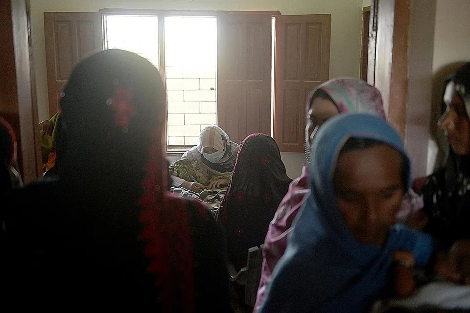 CEKAL KERJA WALAU SERBA KEKURANGAN: Pakar bidan, Dr Maira Yacoob (tengah), kelihatan merawat pesakit sementara puluhan ibu baru bersalin menunggu giliran mereka untuk mendapat rawatan. - Foto-Foto BH oleh HARITH MUSTAFFA