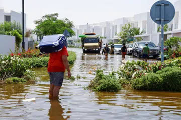 Seorang penduduk membawa bagasinya ketika melalui jalan raya yang dinaiki air akibat hujan lebat di sebuah kawasan kediaman di Dubai, Amiriah Arab Bersatu, pada 18 April. 