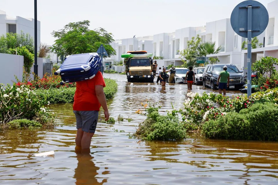 Seorang penduduk membawa bagasinya ketika melalui jalan raya yang dinaiki air akibat hujan lebat di sebuah kawasan kediaman di Dubai, Amiriah Arab Bersatu, pada 18 April. 