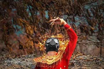 Seorang wanita memakai busana pengantin tradisional Sumatra Selatan menari dengan respirator (alat membantu pernafasan) di kawasan hutan terbakar berhampiran Palembang sebagai sebahagian daripada persembahan seni oleh kumpulan seni Jaga Api.