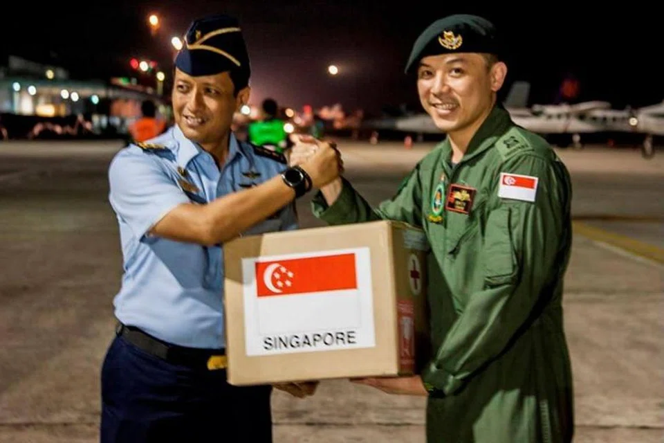 Komander Misi SAF Oh Chun Keong (kanan) menyerahkan pakej bantuan kepada Lt-Kol Ali Sudibyadari TNI di Lapangan Terbang Balikpapan, Indonesia. 