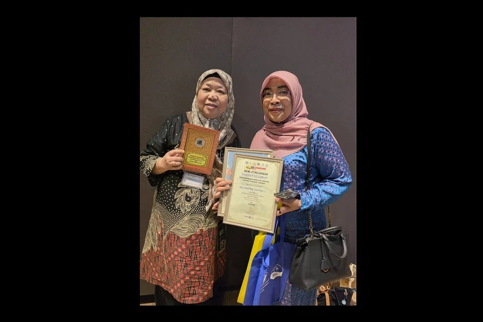 Pasidah Rahmat (kiri) meraih tempat keempat dalam kategori cerpen menerusi karya, ‘Syarat Ke Tujuh.’ Beliau bergambar bersama Ketua Penyelenggara acara Gelanggang Sastera 1, Ezatul Hanim Yahya.
