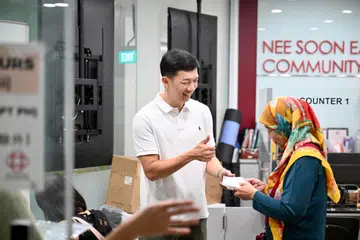 Anggota Parlimen (AP) GRC Nee Soon, Encik Jackson Lam (kiri), telah turun padang di Kelab Masyarakat Nee Soon East pada 15 Oktober untuk membantu proses pengambilan pelitup bagi rakyat yang layak seperti Cik Sutedjowatie Soedarto, 66 tahun (kanan).