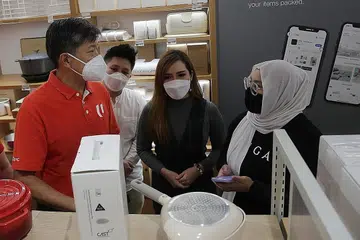 LAWATAN LIHAT LEBIH DEKAT: Encik Ng (kiri, gambar kiri) bertemu dengan kakitangan cawangan runcit IUIGA, termasuk Cik Siti Suhaimah Sairi (kanan), di PLQ Mall semalam untuk memahami operasi runcit mereka. - Foto BH oleh GIN TAY
