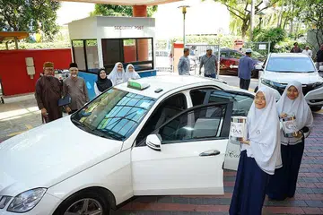 SUMBANG TENAGA: Pelajar Madrasah Aljunied Al-Islamiah dan pemandu teksi bekerjasama dengan TAA untuk meletakkan tabung derma di masjid serata Singapura untuk mengumpul dana sewaku solat Jumaat semalam. - Foto TAA