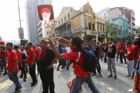  Seorang peserta perhimpunan 'Baju merah' melempar kon trafik ke arah polis rusuhan. Gambar REUTERS 