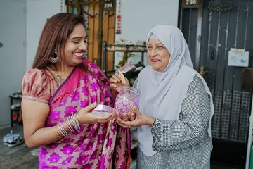 Cik Komathi Manivasan bersama jiran sebelah rumahnya, Cik Zaiton Ahmed, yang seronok dapat rasa dan belajar buat muruku dari Cik Komathi. 