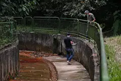 TEMPAT KEJADIAN: Salah seorang daripada dua penyiasat sedang mencatat nota setelah beliau memasuki ke dalam longkang sementara diperhatikan oleh rakan penyiasat. - Foto BH oleh KUA CHEE SIONG