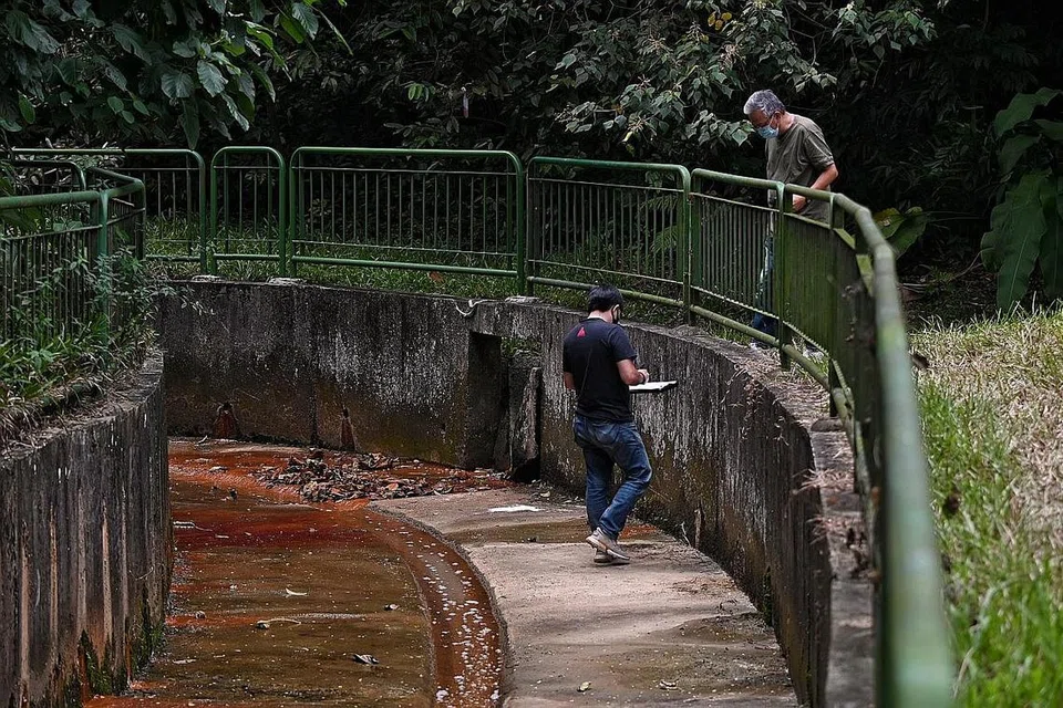 TEMPAT KEJADIAN: Salah seorang daripada dua penyiasat sedang mencatat nota setelah beliau memasuki ke dalam longkang sementara diperhatikan oleh rakan penyiasat. - Foto BH oleh KUA CHEE SIONG