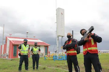 DEMONSTRASI TUGAS: Pegawai pasukan gangguan 'mobile' atau mudah alih (kanan) dan pegawai penguatkuasa lapangan bersama radar sistem pesawat yang tidak dikemudi manusia (tengah) di Lapangan Terbang Changi. - Foto BH oleh ONG WEE JIN 