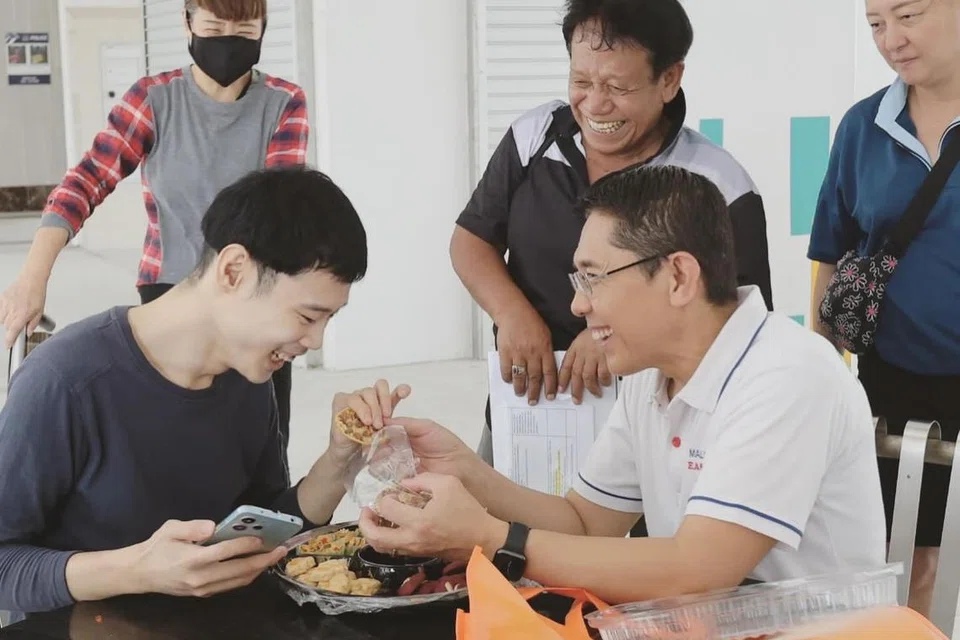 Menteri di Pejabat Perdana Menteri, Dr Mohamad Maliki Osman (kanan,) mengagihkan kuih Raya kepada belia berkeperluan khas Encik Lung Ji Xuan, bagi menyebarkan keceriaan Raya.