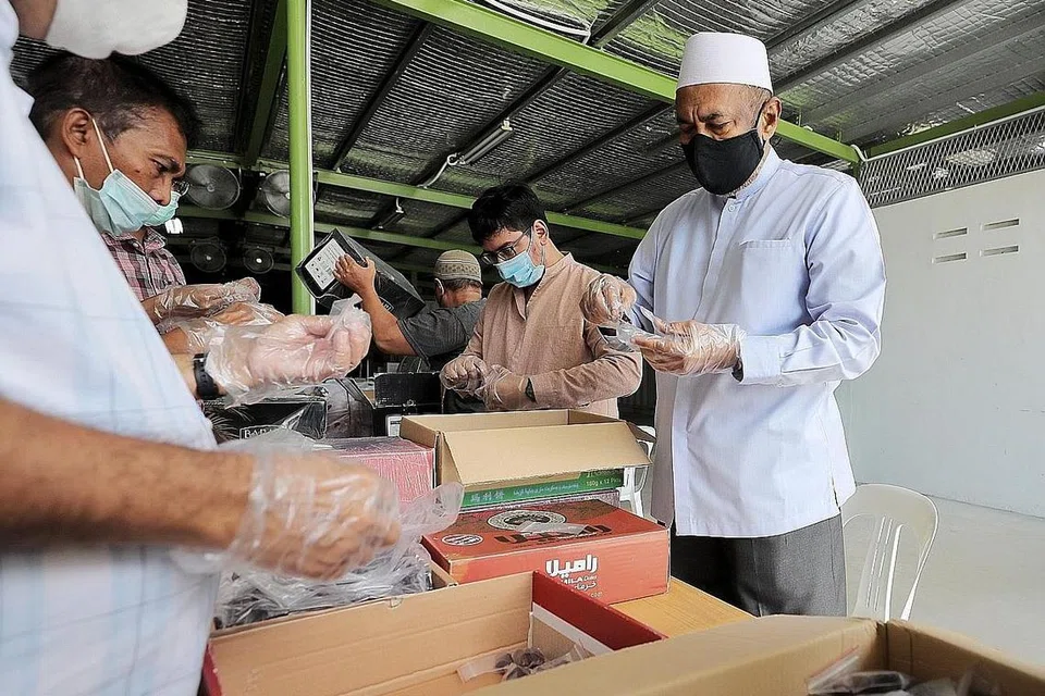 SIAPKAN KURMA: Pengerusi Masjid Khalid, Encik Allaudin Mohamed (kanan), bersama beberapa pembantu di masjid menyiapkan kurma untuk dibahagi-bahagikan kepada jemaah untuk berbuka puasa pada bulan Ramadan ini. Berbeza daripada tahun-tahun sudah, tiada majlis berbuka puasa beramai-ramai akan diadakan pada tahun ini. - Foto-foto BH oleh GAVIN FOO 