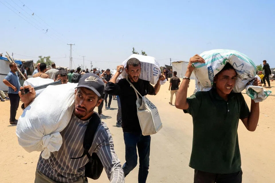 Penduduk Palestin menerima dan membawa bekalan bantuan daripada Yayasan Kemanusiaan Gaza (GHF)  yang disokong Amerika Syarikat, di Rafah, selatan Jaluran Gaza pada 9 Jun 2025.  