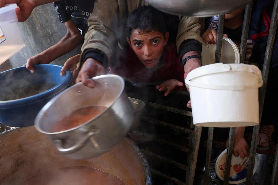KEKURANGAN MAKANAN: Penduduk Gaza termasuk kanak-kanak terpaksa berebut-rebut untuk mendapatkan makanan yang diagihkan oleh sukarelawan ketika pertempuran antara tentera Israel dengan Hamas berterusan di Rafah. 