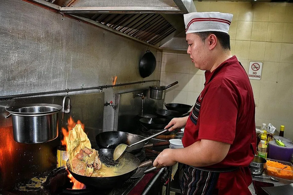 'BERMAIN API': Cef Desmond Lim ketika memasak makanan laut dalam sos telur asin menggunakan api besar di dapur Jom Makan BBQ Seafood. - Foto BM oleh CHONG JUN LIANG