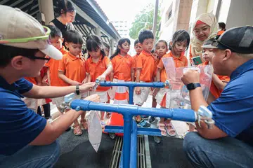 Murid prasekolah My First Skool di Taman Jurong mengambil giliran untuk mengisi beg air daripada paip semasa simulasi gangguan bekalan kepada makanan dan air pada 26 Februari. Paip itu sebahagian daripada van agensi air negara PUB yang mempunyai tangki air untuk membekalkan air sementara.
