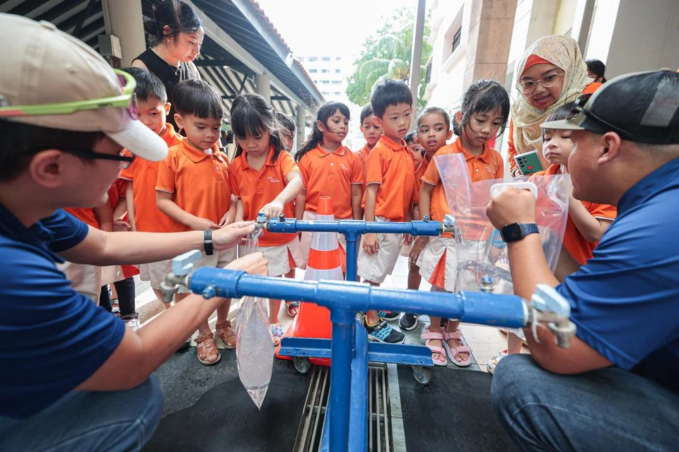 Murid prasekolah My First Skool di Taman Jurong mengambil giliran untuk mengisi beg air daripada paip semasa simulasi gangguan bekalan kepada makanan dan air pada 26 Februari. Paip itu sebahagian daripada van agensi air negara PUB yang mempunyai tangki air untuk membekalkan air sementara.