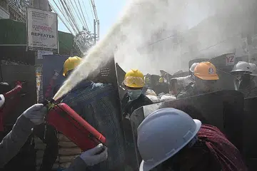 CUBA SELAMATKAN DIRI: Penunjuk perasaan cuba menjejas daya penglihatan pasukan berkuasa dengan menyembur pemadam api yang mengeluarkan kepulan buih bagi menyelamatkan diri, apabila pasukan berkuasa bertindak terhadap pembantah. - Foto AFP