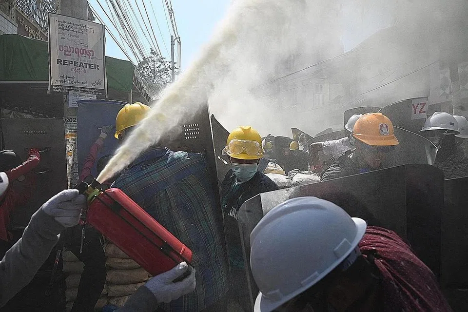 CUBA SELAMATKAN DIRI: Penunjuk perasaan cuba menjejas daya penglihatan pasukan berkuasa dengan menyembur pemadam api yang mengeluarkan kepulan buih bagi menyelamatkan diri, apabila pasukan berkuasa bertindak terhadap pembantah. - Foto AFP