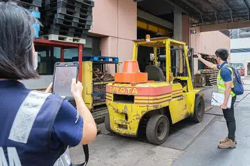 JALANKAN OPERASI PENGUATKUASAAN: Pegawai MOM melakukan pemeriksaan terhadap sebuah kenderaan forklift di sebuah tapak kerja bagi memastikan ia tidak melanggar sebarang peraturan yang boleh membahayakan pekerja. - Foto MOM