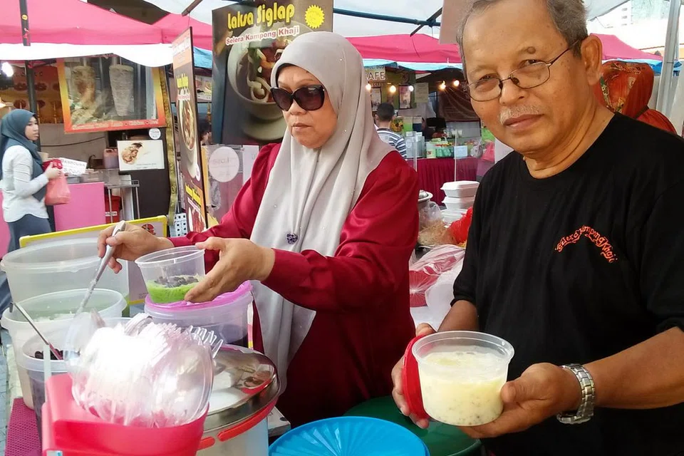 DAPAT SAMBUTAN RAMAI: Encik Makrob dan isterinya, Cik Aisha Yassin (gambar), sedang menyiapkan cendol bowllywood yang mendapat sambutan hangat di kalangan pengunjung gerainya di bazar di Muscat Street. - Foto SAINI SALLEH