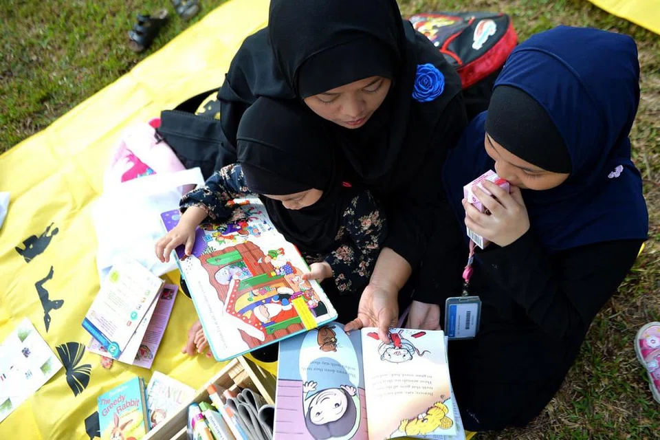 LUANGKAN MASA BERSAMA KELUARGA: Ramai ibu bapa telah membawa anak-anak mereka ke Taman di Persisiran untuk menikmati udara nyaman sambil membaca dan menikmati aktiviti interaktif yang ditawarkan reruai acara tersebut. Mereka juga berpeluang memilih daripada bahan bacaan yang disediakan. - Foto BH oleh KELLY HUI