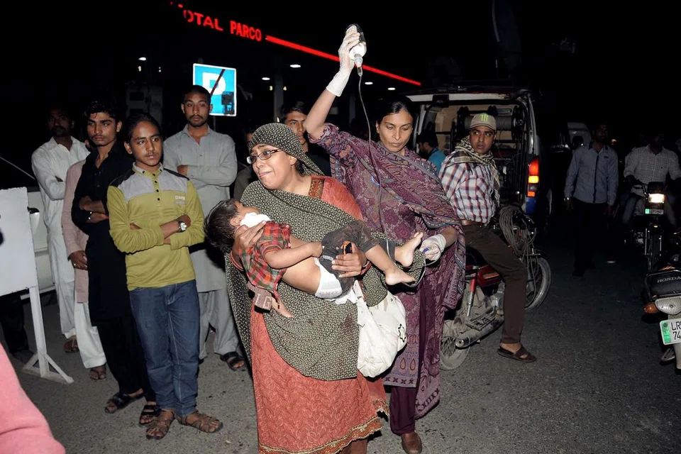 RAMAI CEDERA: Seorang kanak-kanak yang cedera dibawa ke sebuah hospital di Lahore. - Foto AFP