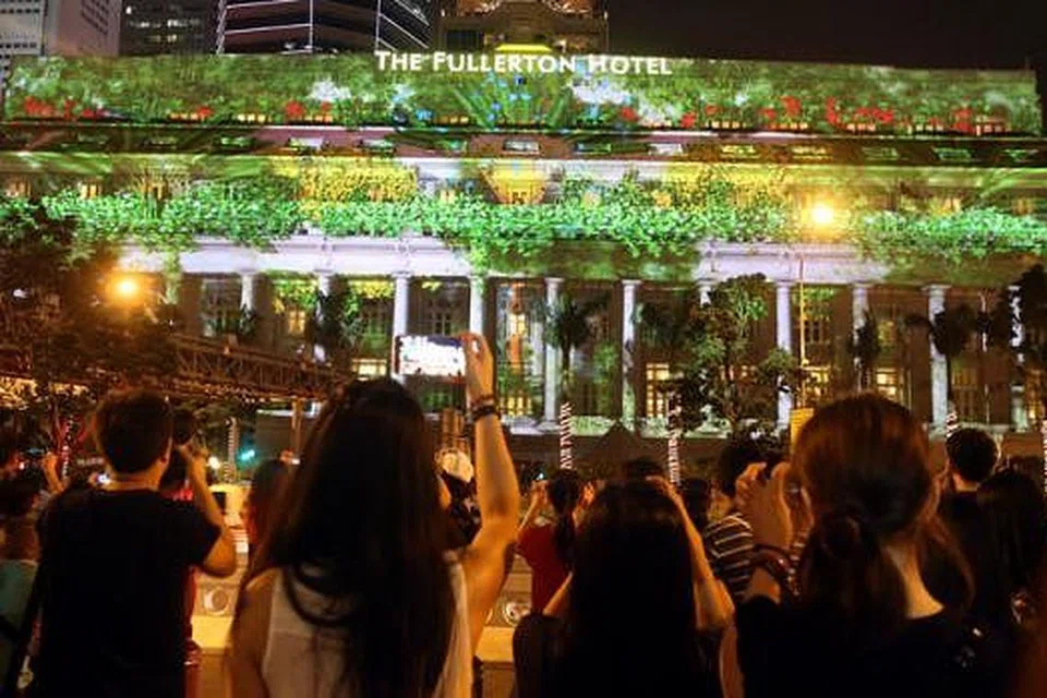 DI SINGAPURA - PERTUNJUKAN LAMPU: Orang ramai menyaksikan pertunjukan lampu khas di hadapan hotel The Fullerton. - Foto ZAOBAO