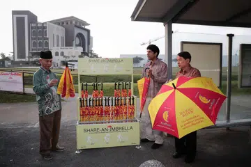 KESELESAAN JEMAAH: (Dari kiri), Encik Mohammad Ayub Johari, Encik Vikram Nair dan Encik Sim Kin Chye, pengerusi CCC Admiralty lancar kempen kongsi payung di Masjid Yusof Ishak semalam. - Foto BH oleh KELVIN CHNG