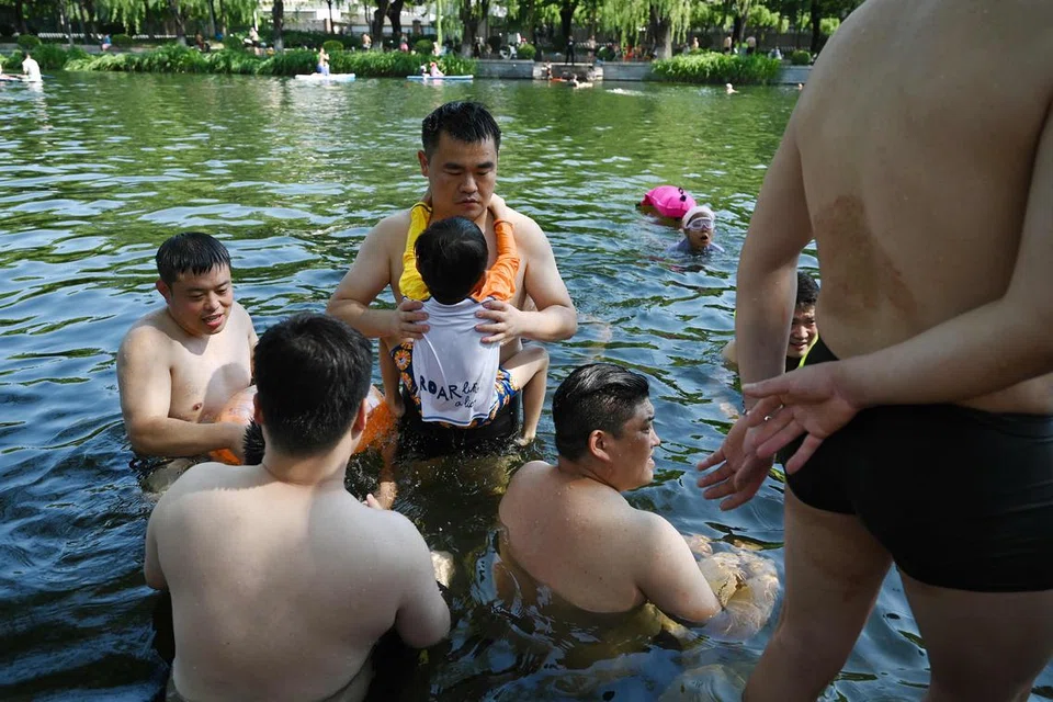 REKOD PANAS: Orang ramai menyejukkan badan di sebuah terusan di Beijing tatkala suhu mencecah 40 darjah Celsius, antara paling tinggi direkodkan di China.