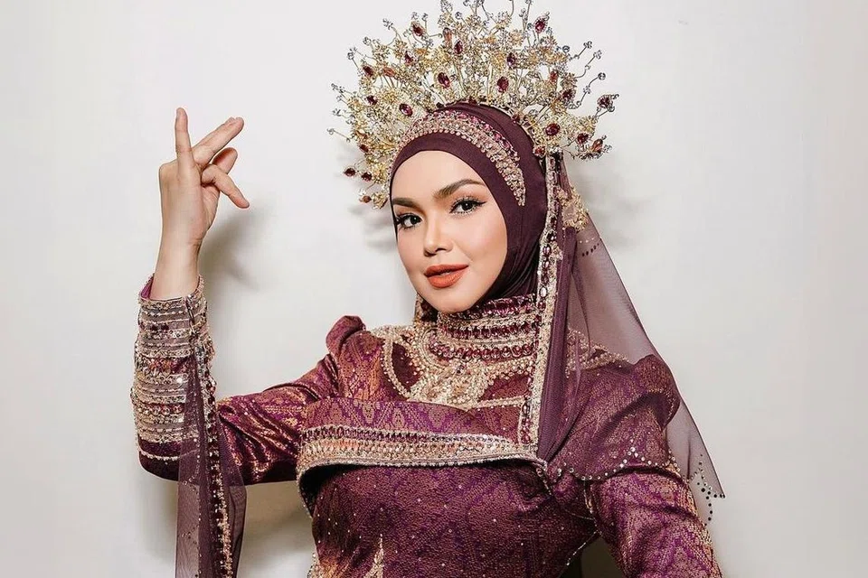 Pakaian yang dihasilkan oleh, Bianca Bell, berwarna merah pulasan ini juga menggunakan songket tenun yang ditambah manik, dan dititupi renda berwarna krim untuk menambah sentuhan klasik, digayakan, Datuk Seri Siti Nurhaliza, di Konsert Fenomena.