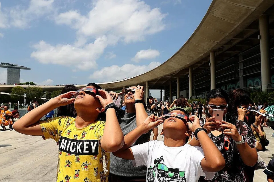 TURUN PADANG: Orang ramai menggunakan cermin mata khas untuk menyaksikan fenomena gerhana matahari di Marina Barrage semalam. - Foto BH oleh WANG HUI FEN 