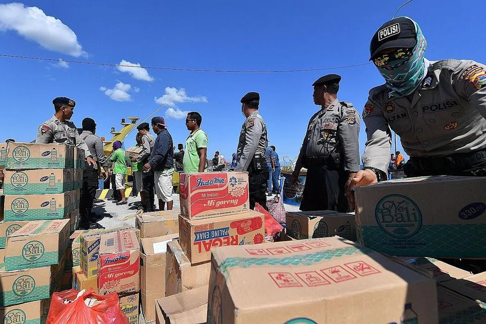 BANTUAN KEMANUSIAAN TIBA: Polis Indonesia dan sukarelawan memunggah bekalan bantuan yang dihantar ke pelabuhan Bangsal di utara Lombok. - Foto AFP