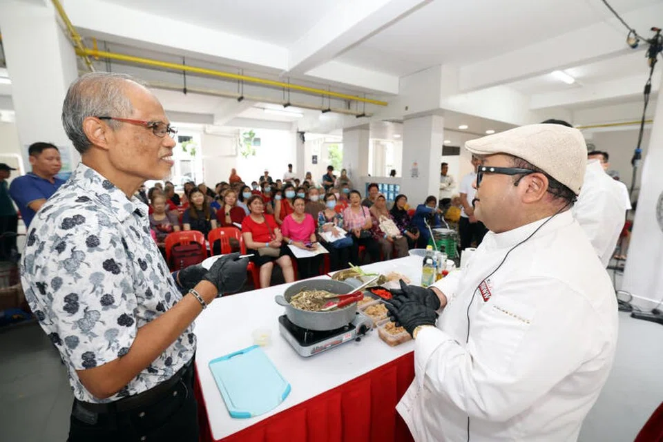 JAGA KESIHATAN: Cef selebriti tempatan, Cef Mel Dean (kanan) menunjukkan penduduk Kolam Ayer dan Encik Masagos (kiri) cara menyediakan masakan sihat di Blok 61, Geylang Bahru. 