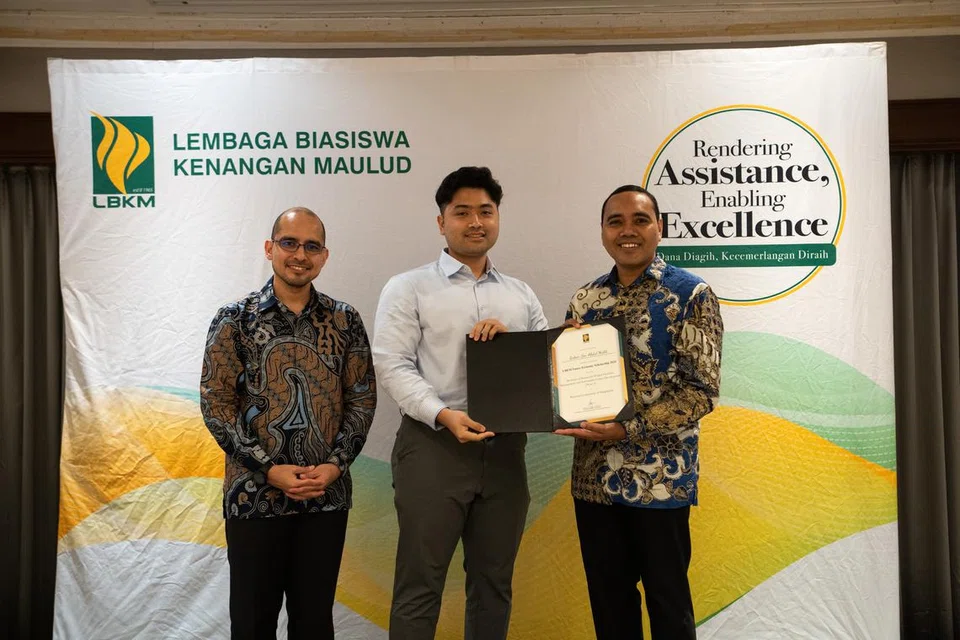 Encik Zaheer Abdul Malik (tengah) menerima Biasiswa Ekonomi Masa Depan daripada tetamu terhormat, Anggota Parlimen (AP) GRC Chua Chu Kang), Encik Zhulkarnain Abdul Rahim, dengan diperhatikan mantan presiden LBKM, Dr Syed Harun Alhabsyi (kiri), yang juga AP GRC Nee Soon, di upacara Anugerah Biasiswa LBKM pada September 2024. 