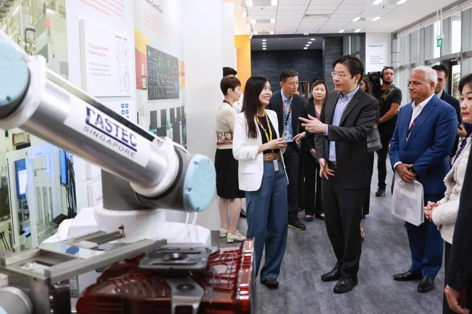 LAWAT KILANG: Encik Lawrence Wong (depan, dua dari kiri) melawat GlobalFoundries semasa majlis perasmian berikutan peluasan kilang tersebut.