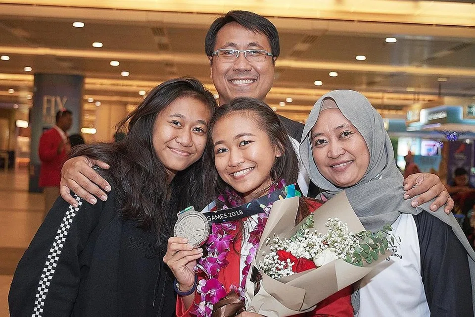 BERSAMA KELUARGA: Pemenang pingat perak Nurzuhairah Yazid (depan, tengah) bersama keluarga. Nurzianah Yazid (depan kiri); ibu Norah Masaod (depan kanan) dan bapa Mohammad Yazid. - Foto BH oleh LIN ZHAOWEI