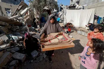 BANTUAN SUKAR DIKIRIM: Seorang wanita dilihat membawa dua keping roti ketika berjalan di celah-celah bangunan yang telah musnah akibat pengeboman Israel di Rafah, di selatan Gaza yang bersempadankan Mesir.