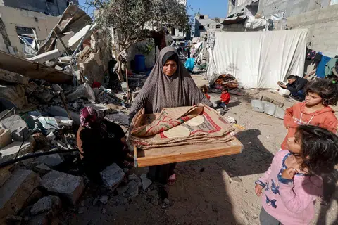 BANTUAN SUKAR DIKIRIM: Seorang wanita dilihat membawa dua keping roti ketika berjalan di celah-celah bangunan yang telah musnah akibat pengeboman Israel di Rafah, di selatan Gaza yang bersempadankan Mesir.