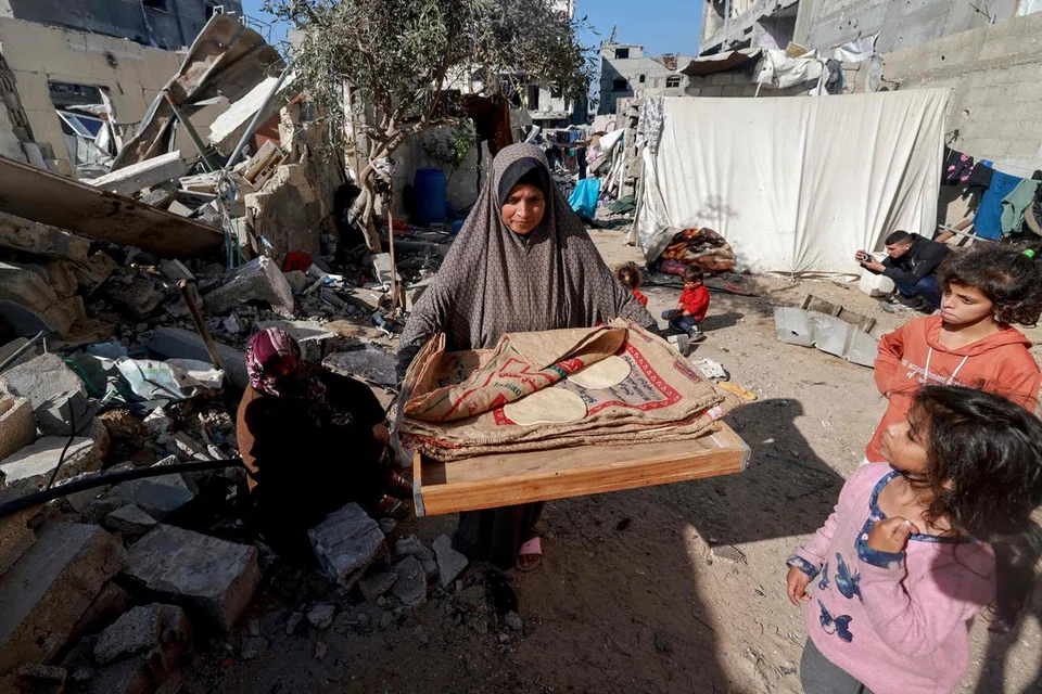 BANTUAN SUKAR DIKIRIM: Seorang wanita dilihat membawa dua keping roti ketika berjalan di celah-celah bangunan yang telah musnah akibat pengeboman Israel di Rafah, di selatan Gaza yang bersempadankan Mesir.