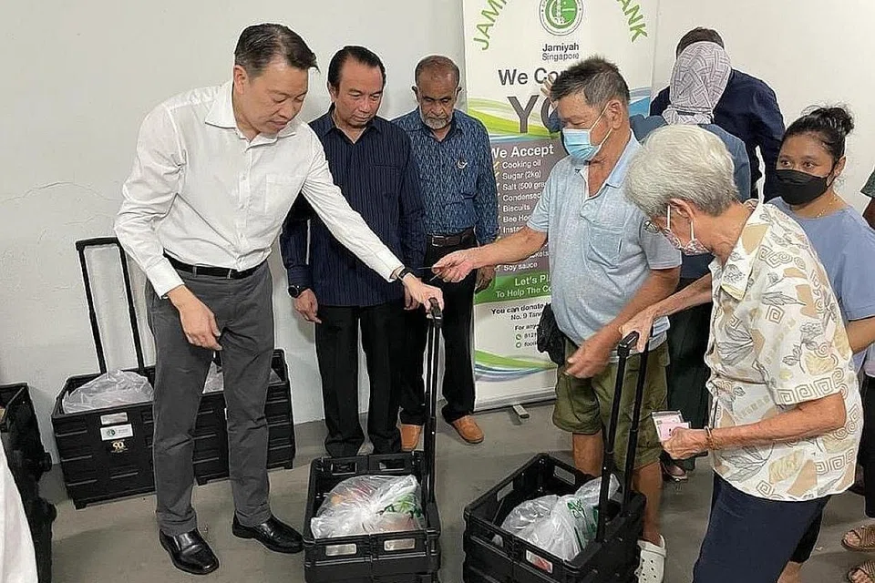 BERSAMA MEMBANTU: Encik Melvin Yong (kiri) dan Dr Mohd Hasbi (dua dari kiri) membantu penduduk Radin Mas menerima habuan makanan selepas majlis menandatangi MOU bagi Jampacked@Radin Mas di Blok 106 Jalan Bukit Merah, bank makanan yang dijangka siap April depan. - Foto MEVIN YONG / FACEBOOK