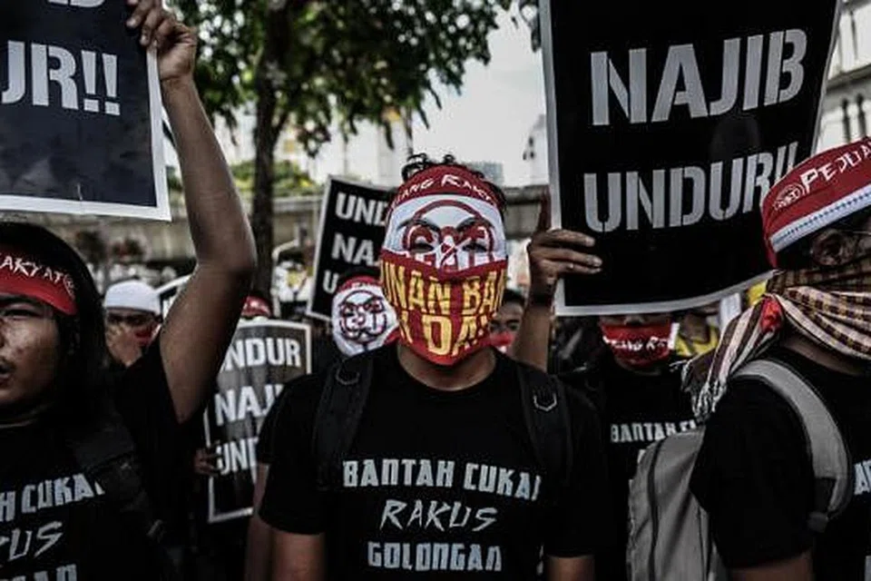 TIDAK PUAS HATI: Penunjuk perasaan memakai topeng sambil berarak ke mercu tanda Malaysia sebagai membantah pelaksanaan GST. - Foto AFP