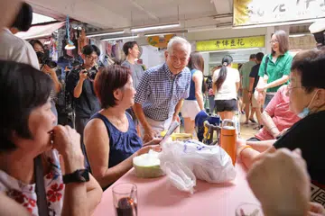 TEMUI ORANG RAMAI: Calon Pilihan Raya Presiden, Encik Ng Kok Song, beramah mesra dengan penduduk semasa kunjungannya ke Pasar dan Pusat Makanan Chong Pang pada pagi Sabtu. Beliau diiringi tunangnya, Cik Sybil Lau (baju hijau, kanan).