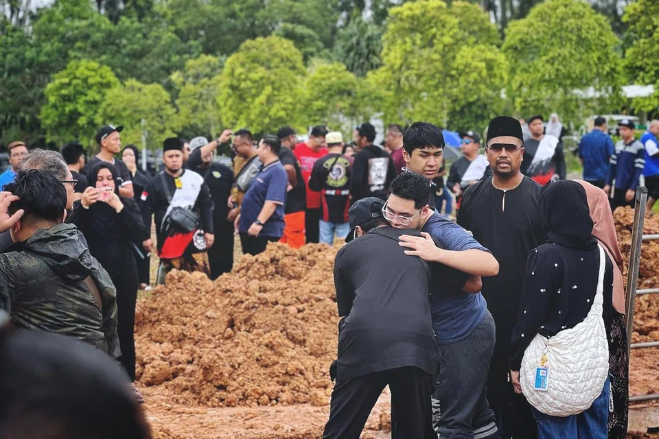 Anak sulung Allahyarham Nur Mohammad Azmi, Encik Sofyan Nur Mohammad, kelihatan sedang memeluk seorang ahli keluarga dalam di upacara pengebumian yang dihadiri ratusan orang.