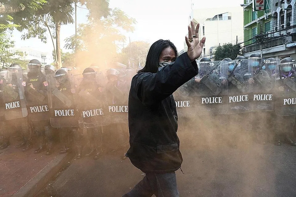 TUNJUK PERASAAN: Seorang penunjuk perasaan pro-demokrasi memberi isyarat di hadapan polis rusuhan ketika mereka mengambil bahagian dalam demonstrasi untuk mengecam penggunaan undang-undang lese majeste, di Bangkok pada 10 Disember 2020. - Foto AFP
