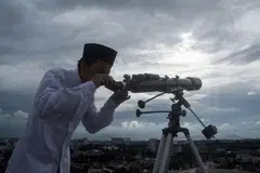 Seorang anggota jemaah Muslim menggunakan teleskop untuk melihat kemunculan anak bulan yang menandakan permulaan bulan suci Ramadan di Bandung, Jawa Barat pada 17 Februari 2026. 