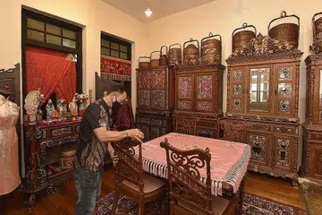  MUZIUM PRIVET: Salah seorang penjaga muzium, Encik Eric Ang, mengatur kerusi antik kayu di galeri tingkat atas di Rumah Antik Katong. Di latar belakangnya adalah beberapa bakul perkahwinan di atas kabinet antik Peranakan. - Foto BH oleh DESMOND WEE
