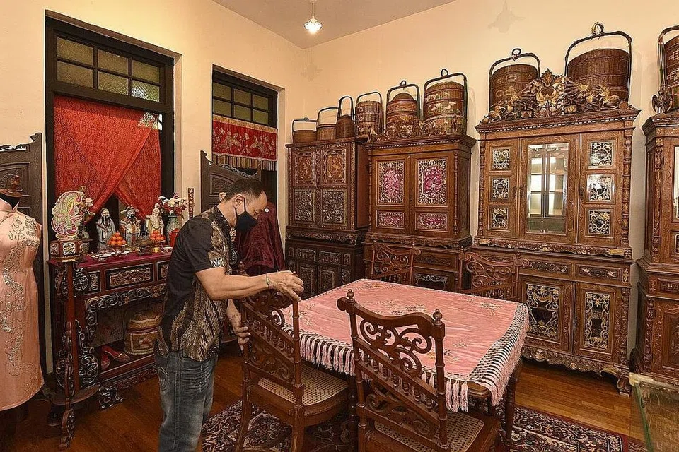  MUZIUM PRIVET: Salah seorang penjaga muzium, Encik Eric Ang, mengatur kerusi antik kayu di galeri tingkat atas di Rumah Antik Katong. Di latar belakangnya adalah beberapa bakul perkahwinan di atas kabinet antik Peranakan. - Foto BH oleh DESMOND WEE