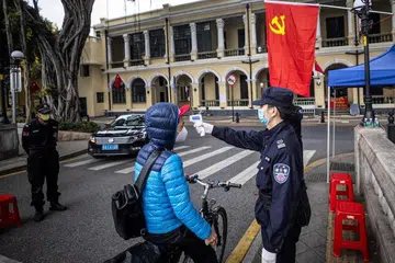 AMBIL SUHU: Pengawal keselamatan memeriksa suhu orang ramai di sekatan jalan raya di Guangzhou, China pada 10 Februari lalu.
