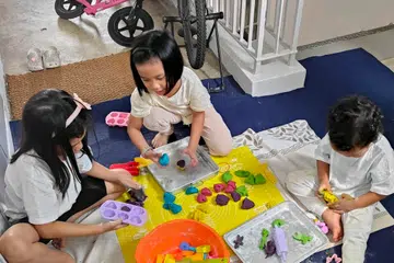 Anak-anak penulis, (dari kanan) Hamzah Mohammad Hanafi dan Munawwarah Mohammad Hanafi, bermain doh mainan yang dibuat sendiri bersama jiran mereka, Xena Lim, di koridor.